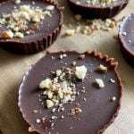 Close-up of round Peanut Butter Cups with a smooth top, sprinkled with chopped nuts, arranged on a wooden surface.