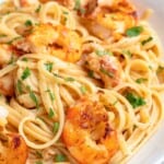 A plate of Lemon Shrimp Pasta featuring linguine topped with grilled shrimp, garnished with fresh parsley and served with a lemon wedge.