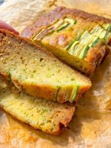 Close-up of an Easy Zucchini Bread loaf sliced on parchment paper, highlighting the moist texture and pieces of zucchini baked into the golden-brown crust.
