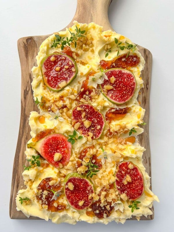A wooden board topped with swirls of butter, fresh fig slices, crushed nuts, herbs, and honey drizzles—discover how to make a butter board that's perfect as an appetizer or elegant spread for any occasion.