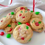 A plate of holiday cookies with red and green candy-coated chocolates, displayed on a white surface with a red ribbon in the background, brings festive flair to any Holiday Charcuterie Board.