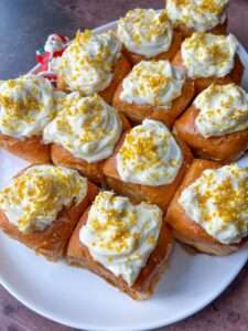 A plate of Lazy Cinnamon Buns topped with white icing and golden sprinkles, arranged closely together on a white dish.