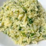 A close-up of a plate of Spinach Orzo Salad, featuring orzo pasta mixed with fresh herbs and a light, creamy sauce, served on a white dish.