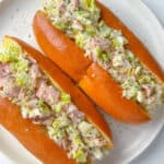 Two soft sandwich rolls filled with a creamy Italian Chopped Sandwich mixture of ham, lettuce, and herbs are served on a white plate.