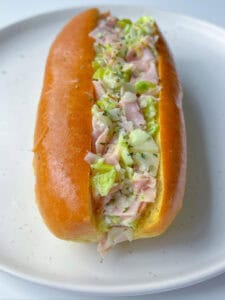 A soft bun filled with chopped ham, lettuce, and mayonnaise, served on a white plate—this Italian Chopped Sandwich brings classic flavors together in every bite.