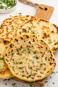 Delicious homemade naan with melted cheese, served hot and garnished with fresh herbs. Perfect for comforting meals.