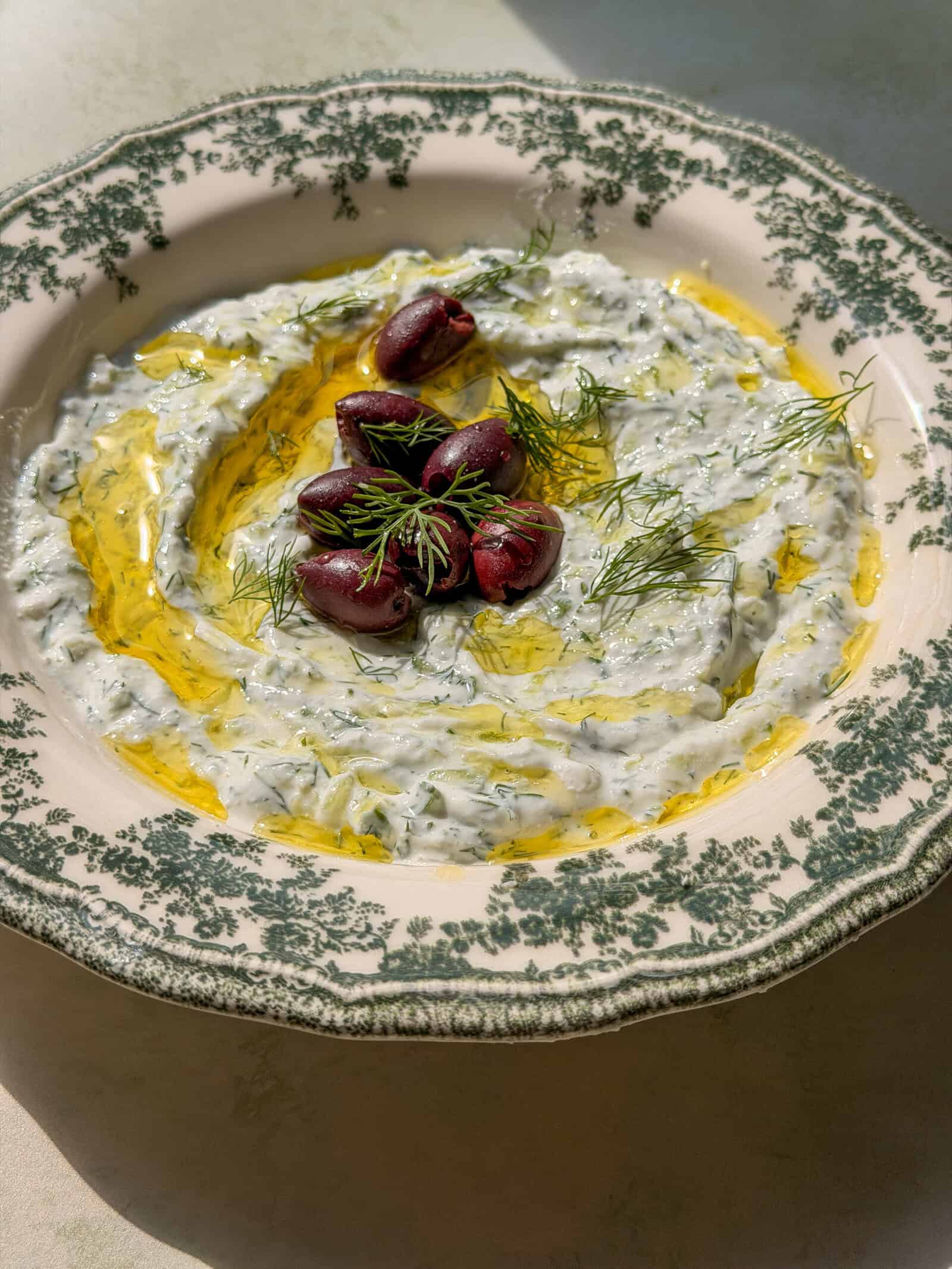 Creamy tzatziki with Kalamata olives and dill on decorative plate