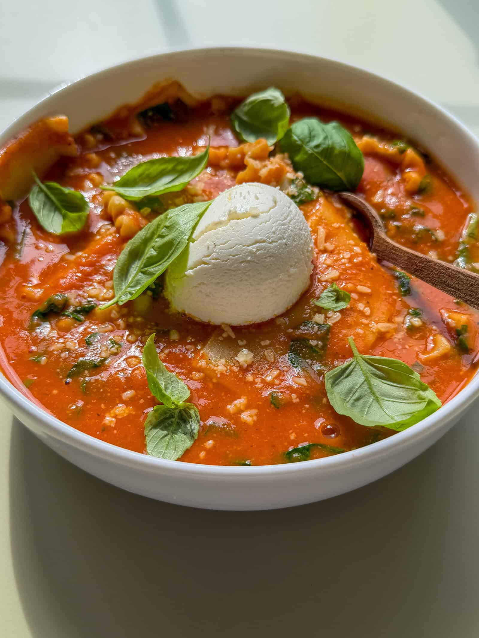 High fibre lasagna soup with a dollop of ricotta on top and baby basil leaves