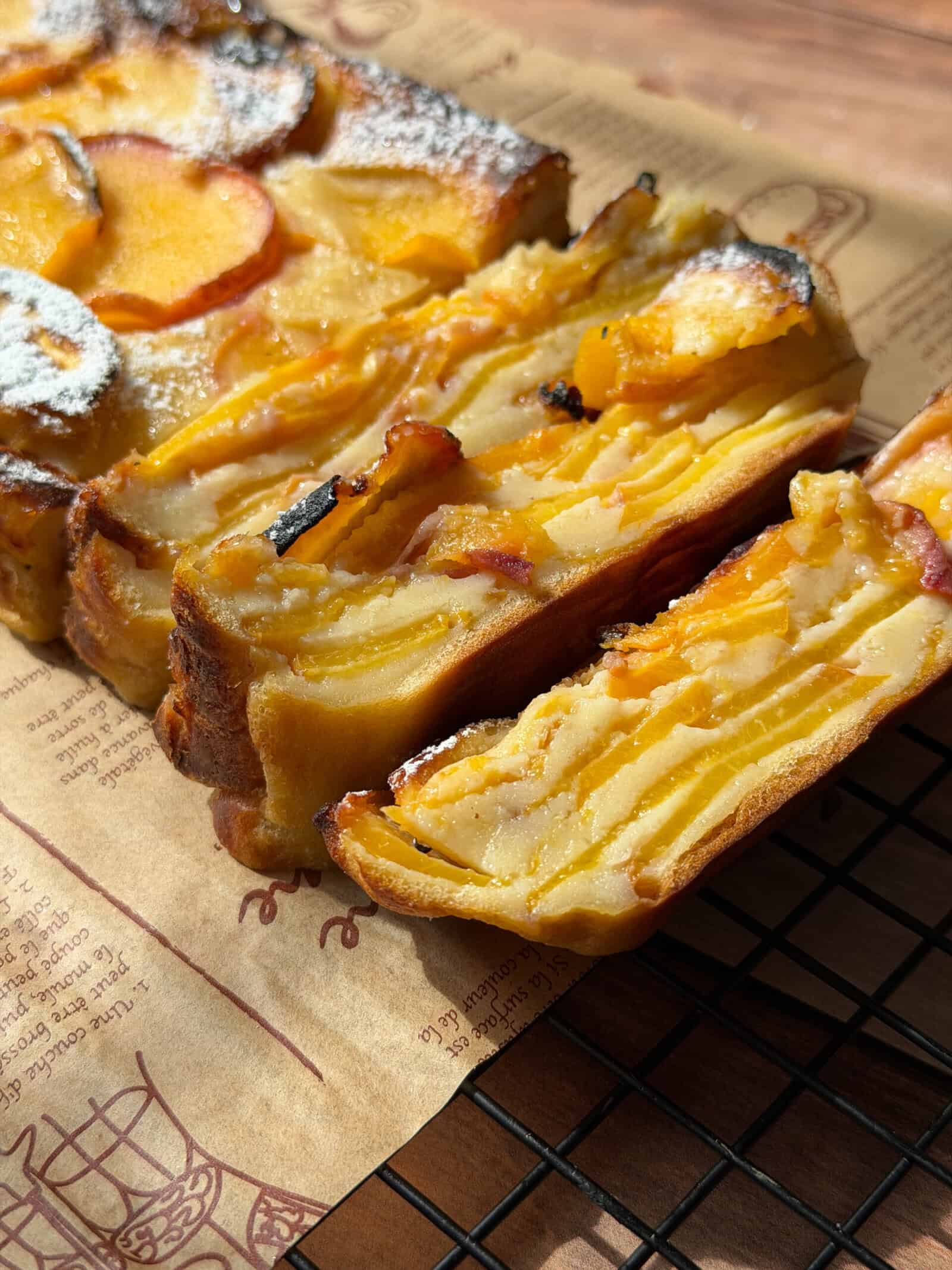 Sliced peach custard cake on a wire cooling rack