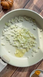 Diced onions sautéing in oil in a white pan
