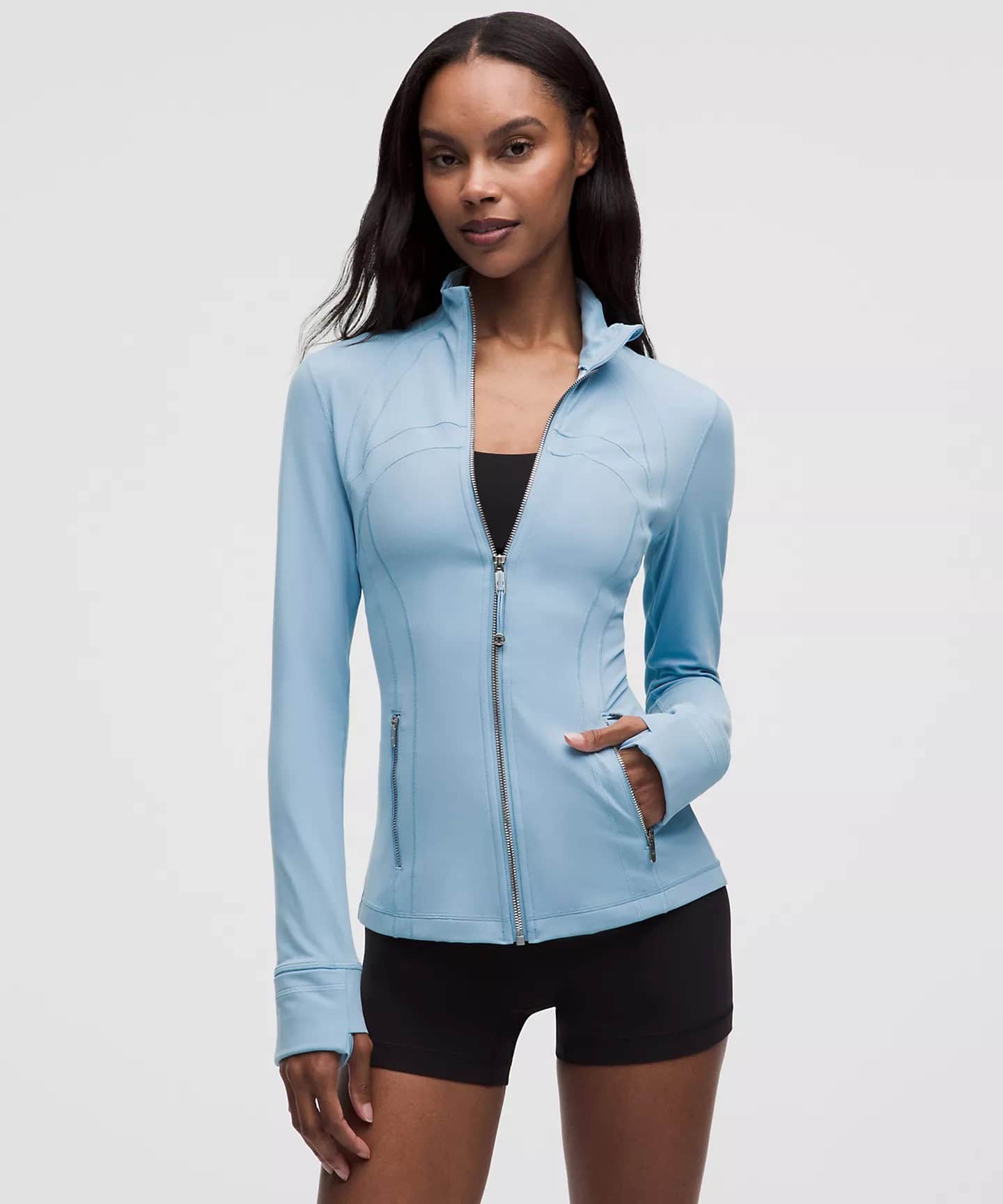 Woman wearing light blue zip-up athletic jacket and black shorts