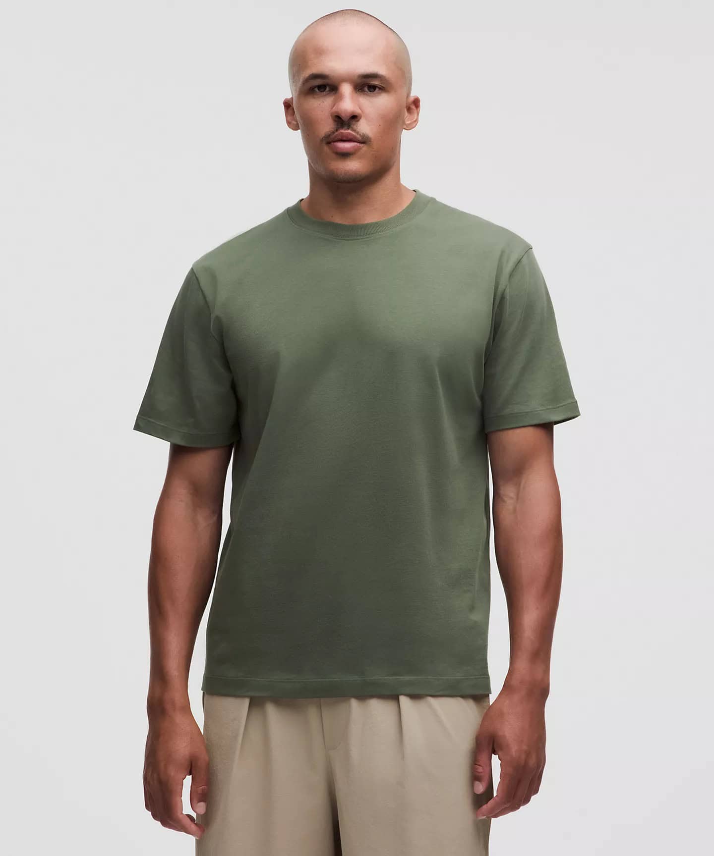 Man wearing olive green crew neck t-shirt with beige pants