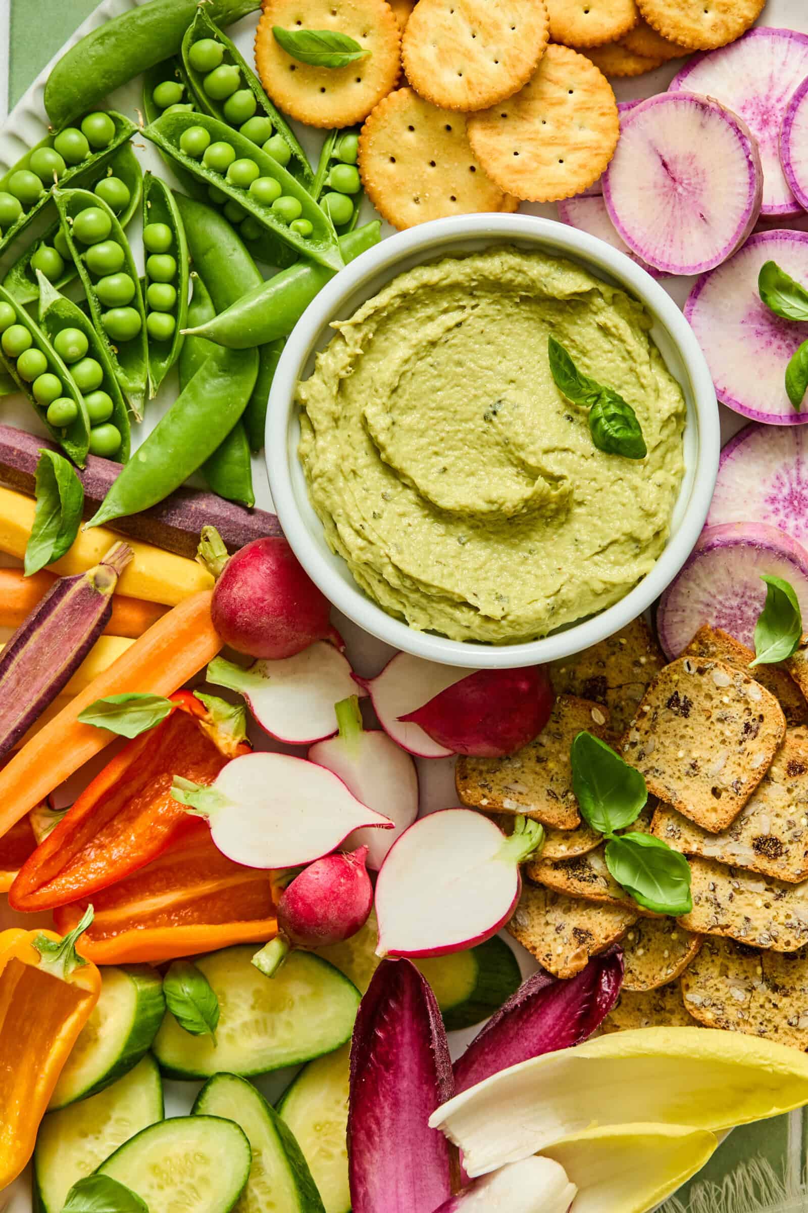 Colorful vegetable platter with green avocado dip and crackers