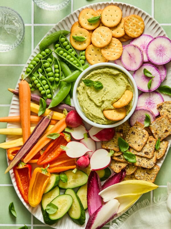Colorful vegetable and cracker platter with green hummus dip