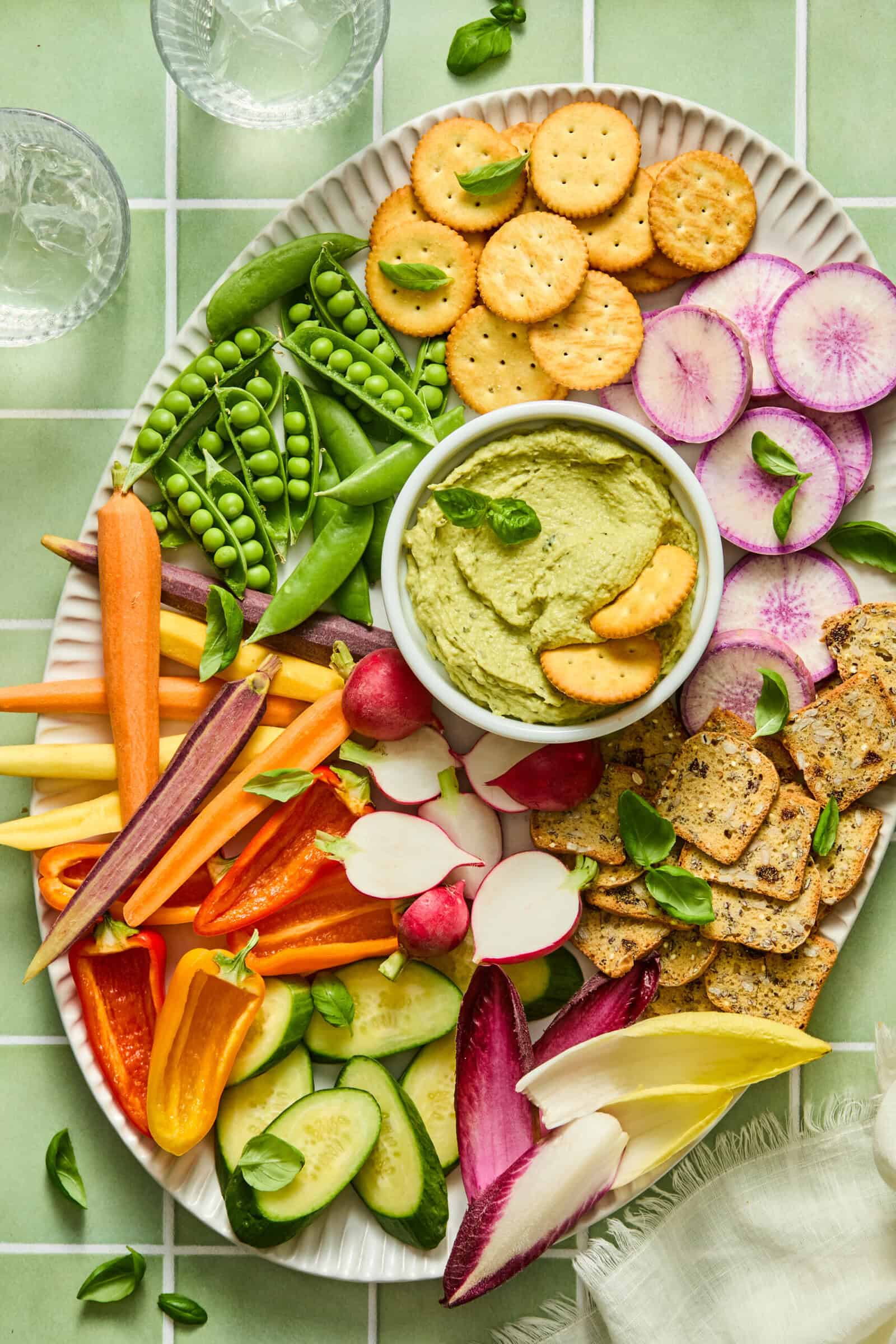Colorful vegetable and cracker platter with green hummus dip