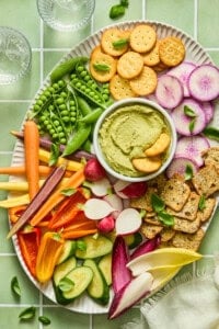 Colorful vegetable and cracker platter with green avocado dip