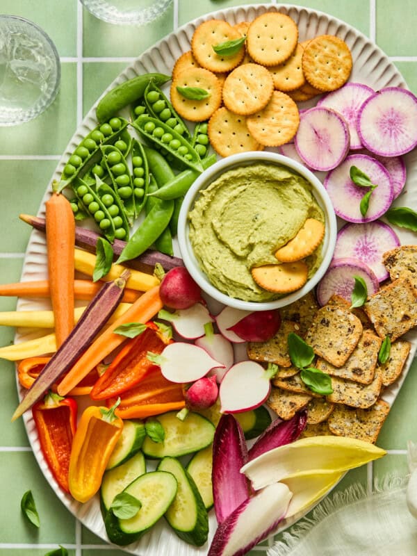 Colorful vegetable and cracker platter with green avocado dip