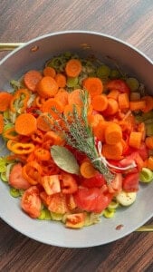Fresh chopped vegetables with herb bouquet in a pan